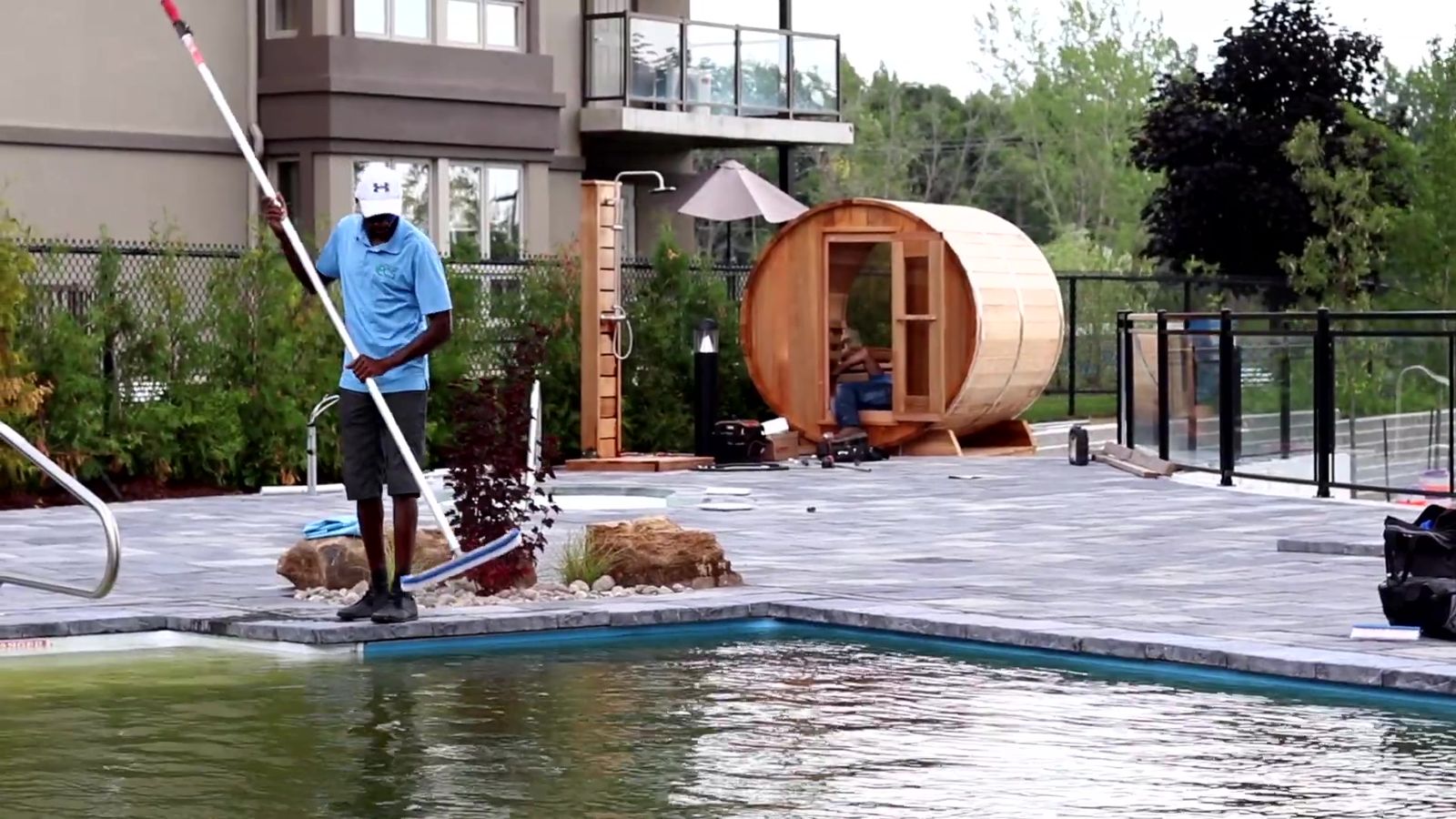Technicien d'Entretien PCS qui brosse les parois de la piscine d'un immeuble en copropriété