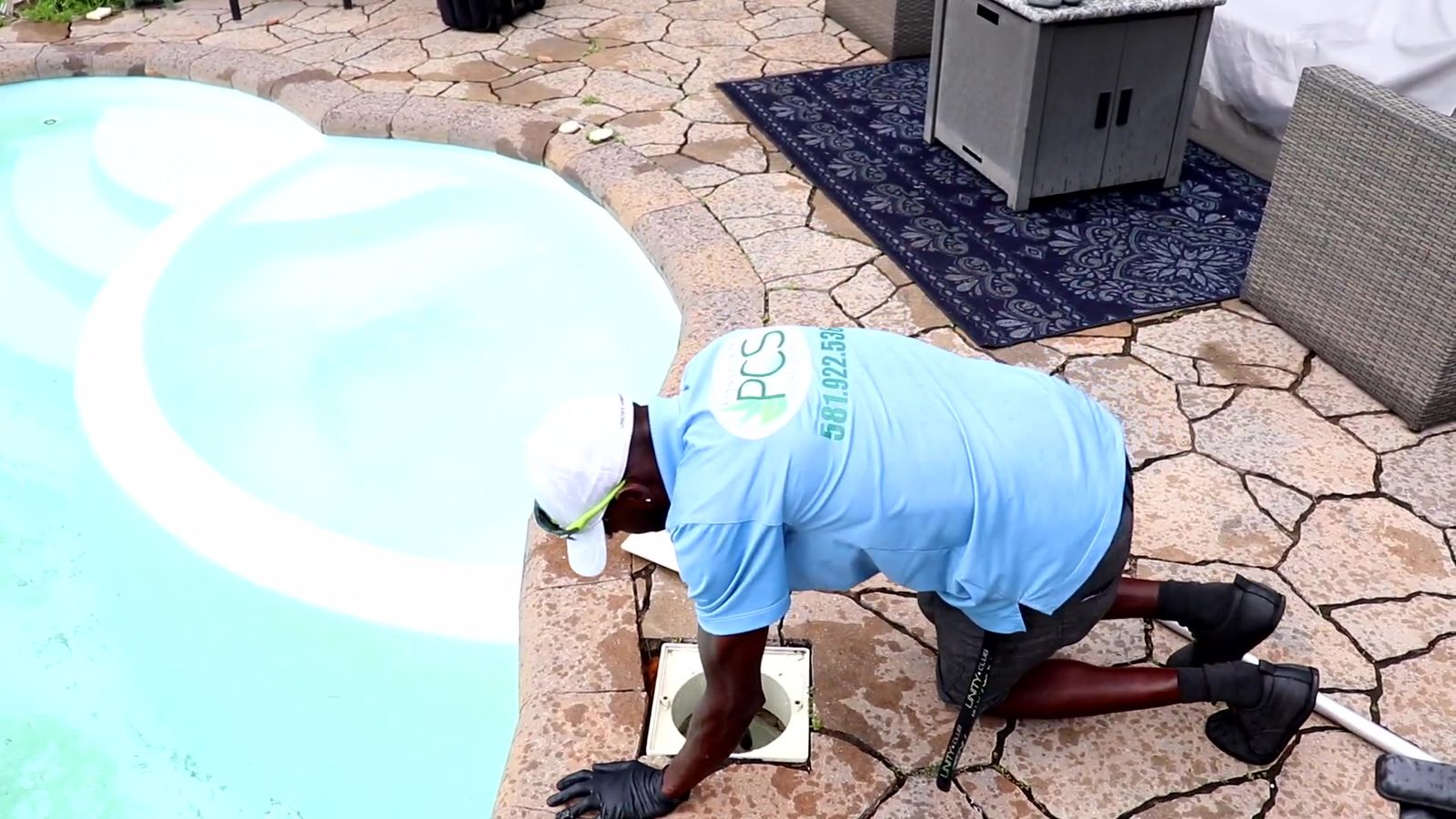 Technicien d'Entretien PCS, à genoux au bord d'une piscine, qui vide le panier de l'écumoire